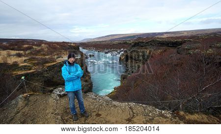 Young Asian man with blur outdoor jacket travel to Iceland and visit Hraunfossar waterfall