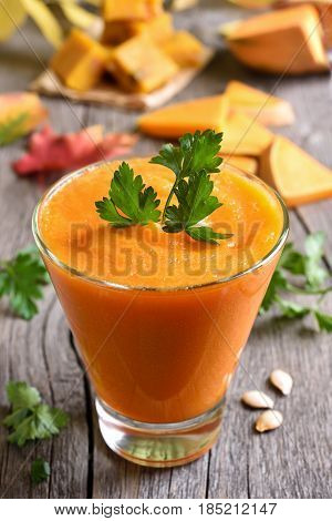 Pumpkin puree smoothie in glass on wooden background close up view