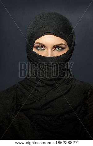 Beautiful muslim woman in niqab traditional veil against on dark background