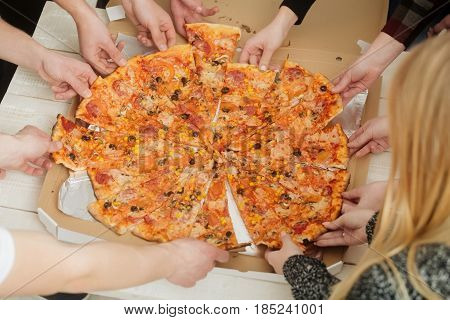 Human hands taking fat tasty big fresh cooked italian pizza slices from delivery box package. Addiction of eating unhealthy meals. Fast food teamwork