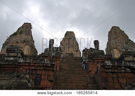 A woman climbing the stairs in a temple of Ankor Wat. Cambodia