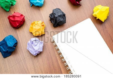 Open Blank White Book With Group Of Colorful Crumpled Paper Ball On Dark Brown Table Top, Business B