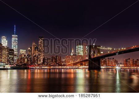 Brooklyn Bridge in the evening with midnight blue sky and smooth water surface Manhattan downtown