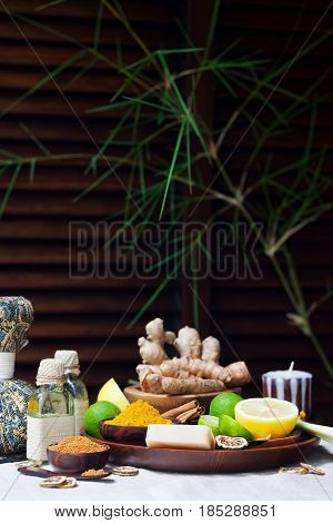 Spa heath care set of essential oils soap ginger turmeric roots and spices on a plate. Brown wooden background. Copy space