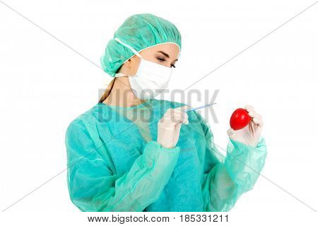 Young female cardiologist surgeron holding heart and scalpel