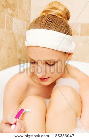 Young caucasian woman shaving legs