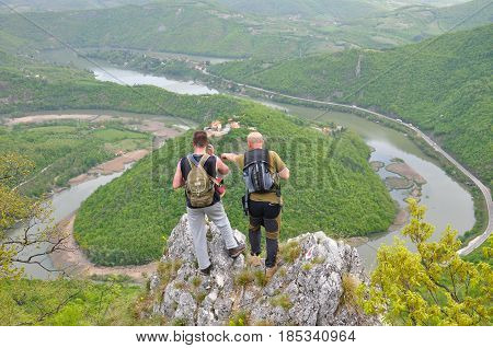 Hikers on top of a mountain enjoy the beautiful view of nature, forest and river in valley. View on meanders of Morava river  from Kablar, Serbia