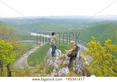Hikers on top of a mountain enjoy the beautiful view of nature, forest and river in valley. View on meanders of Morava river  from Kablar, Serbia