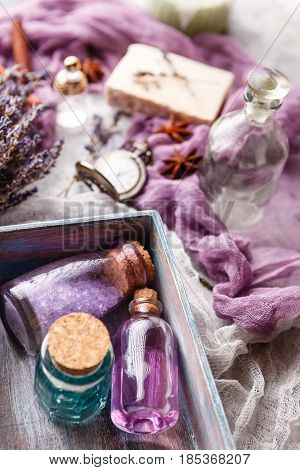 Bottle with aromatic lavender oil and sea salt in a wooden box a bottle of perfume a bouquet of lavender piece of soap and a vintage pocket watch. Selective focus. Spa and perfume theme