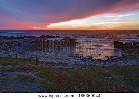 HDR image of dramatic clouds at sunset over the rocks and sand of Asilomar State Beach in Pacific Grove on the Monterey Peninsula of California