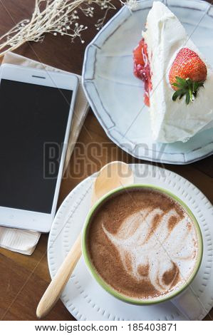 coffee cup and delicious cake strawberry and relax time moblie on table in coffee shop