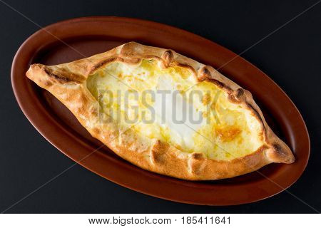 Adjarian khachapuri with eggs close up on black background. Top view