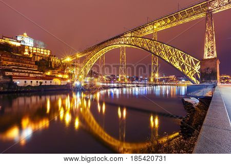 Dom Luis I or Luiz I iron arch bridge across Douro river with reflection and Monastery of Serra of Pilar in Porto at night, Portugal.