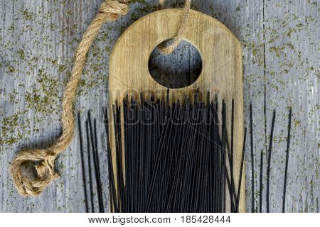 a pile of uncooked black spaghetti on a wooden chopping board, placed on a gray rustic wooden table