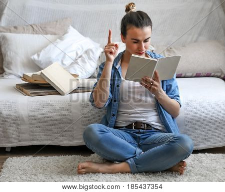 girl reading a book in a cozy room on the couch with a Cup of tea , the concept of leisure, and comfort