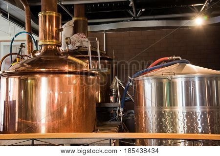 mini brewery with brewing kettles vessels tubs and pipes made of stainless steel.
