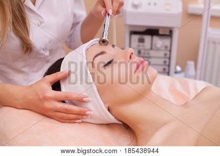 The Doctor-cosmetologist Makes The Procedure Microdermabrasion Of The Facial Skin Of A Beautiful, Yo