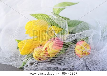 Yellow tulips on a white airy cloth texture
