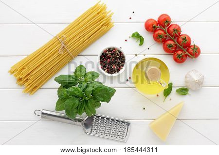Bucatini with tomatoes basil oil cheese and spices on white wooden background. Italian pasta with other ingredients for cooking mediterranean dish. Top view concept healthy food.