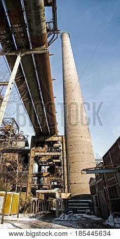 Panorama of industrial plant pipeline chimney in winter snow ice steel rust