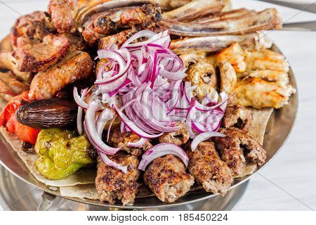 Meat plate with delicious pieces of meat ribs grilled potatoes and mushrooms with onion. Close up image with selective focus.