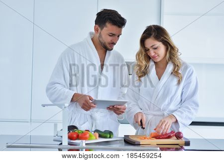 Couple in home kitchen using electronic tablet.