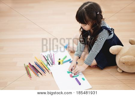 Portrait of beautiful kid having art activity on the floor selective focused.