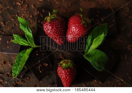 Delicious still life with juicy strawberry berries mint leaves and tiled chocolate.