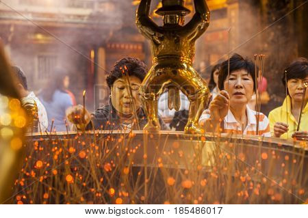Taipei Taiwan - 6 October 2012: People praying and lighting incense at Longshan Temple in the center of the city