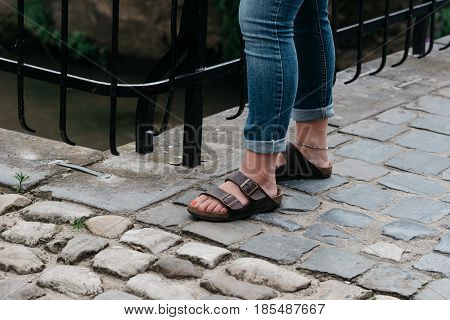 Young woman wearing sandals in cobblestone pavement of medieval city