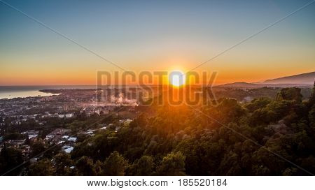 View from the quadrocopter to the bright sunset over the sea and evening city