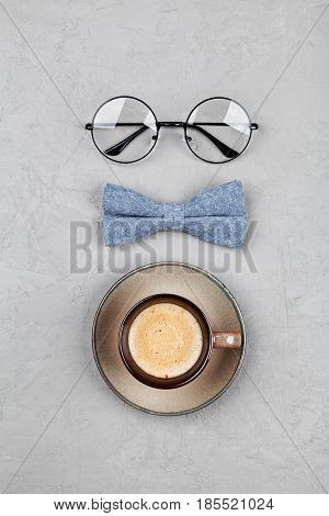 Happy Fathers Day background with morning coffee mug glasses and bowtie on stone gray table top view in flat lay style.