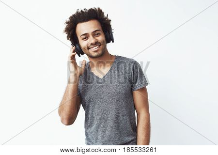 Portrait of handsome african man in headphones listening to music over white background. Copy space.