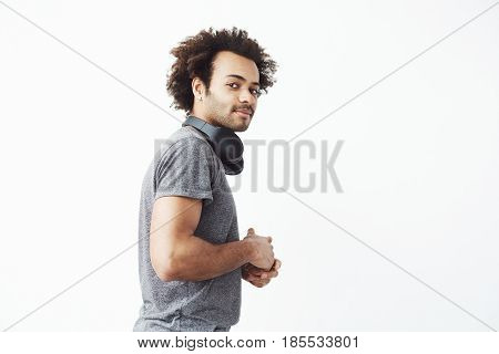 Young handsome african man looking at camera standing in profile over white background. Copy space.