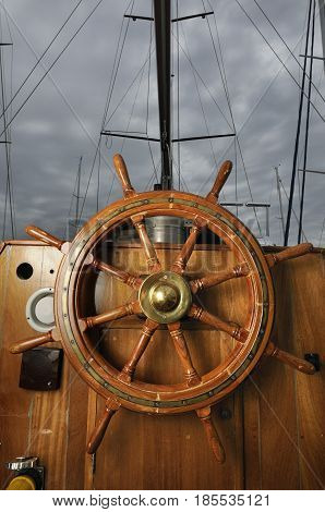 steering wheel sailboat wooden under a cloudy sky