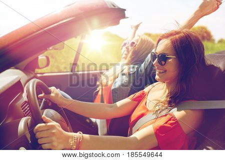 summer holidays, road trip, vacation, travel and people concept - smiling young women driving in in cabriolet car