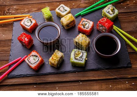 Sushi Set rolls with soy sauce served on gray stone slate on wooden background