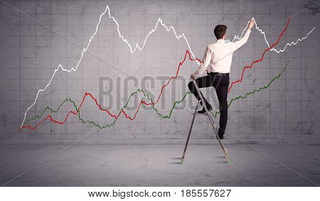 A guy in modern suit standing on a small ladder and drawing a chart on grey wall background with exponential progressing curves, lines