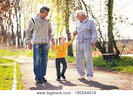 Two grandfather walking with the grandson in the park
