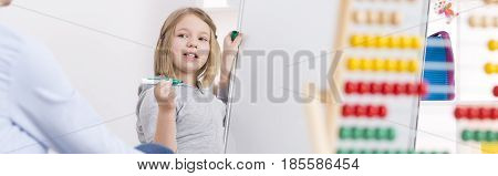 Girl during extra classes writing on a white board