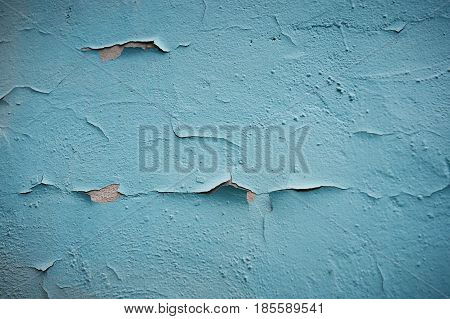 Grunge Background. Wall with the colored turquoise whitewash falling off fragment as a background texture cracked