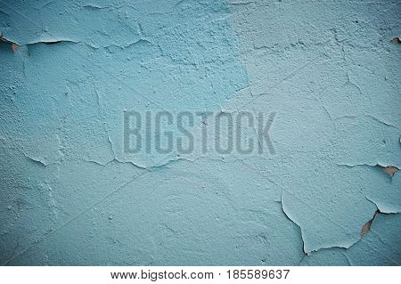 Grunge Background. Wall with the colored turquoise whitewash falling off fragment as a background texture cracked