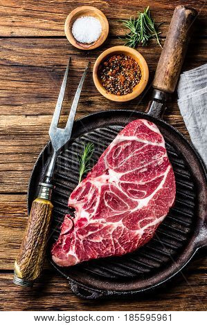 Meat. Raw beef marbled meat steak on vintage cast iron grill pan and spices on wooden rustic background. Top view