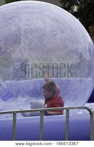 Cornwall, Quebec - July 26, 2014 - Vertical of a young boy playing inside large plastic bubble in a pool at the Ribfest in Cornwall, Ontario on a sunny afternoon in July.