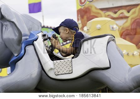 Cornwall, Quebec - July 26, 2014 - Wide view of a young boy enjoying a carnival fun ride at the Ribfest in Cornwall, Ontario on a sunny afternoon in July.