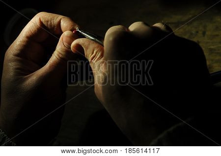 Making of jewelry. Jeweller is stringing the coral bead on the silver wire.
