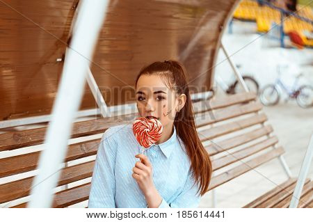 Tinted portrait of a young girl in a shirt sitting on a wooden bench
