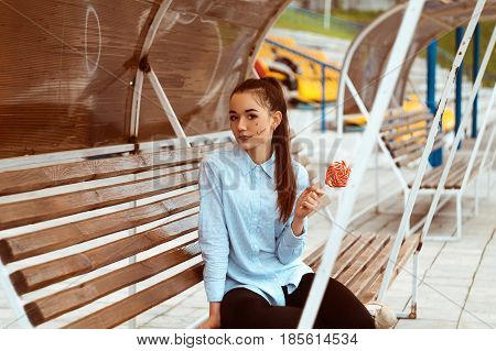 Tinted portrait of a young girl in a shirt sitting on a wooden bench