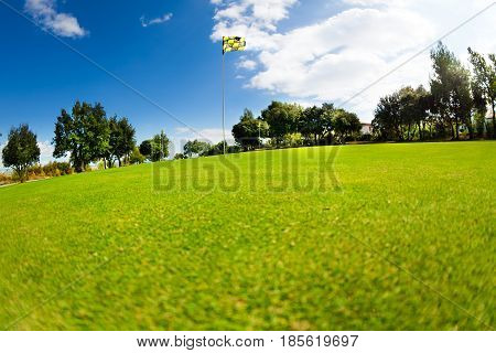 Beautiful scenery of green golf course with flagstick in the distance at sunny day