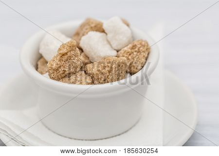 White sugar and brown sugar cane cube in white bowl on white background. Close up image.